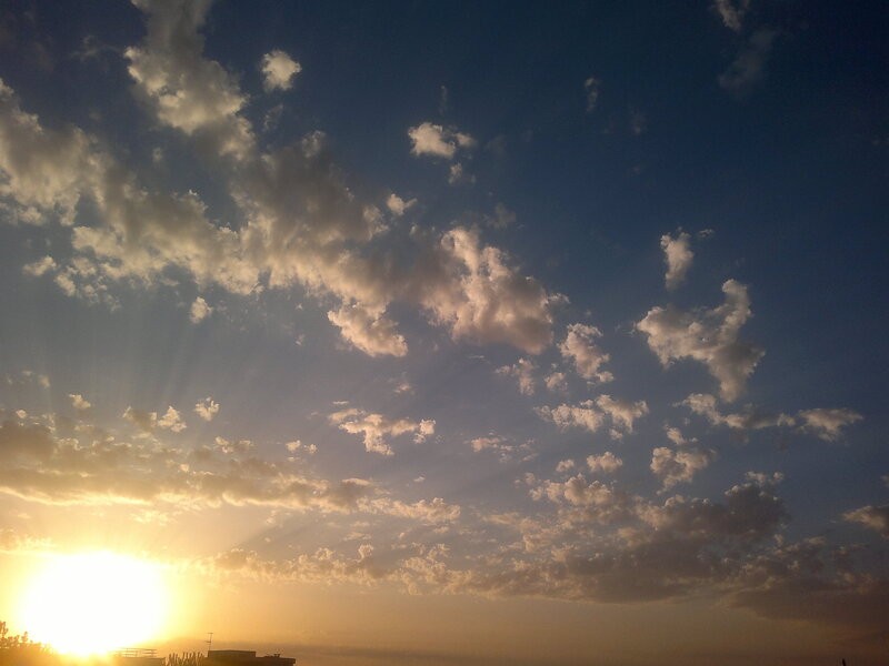 Sun Setting Behind Clouds — Blue, Serene, Sunset, Photograph, Buildings