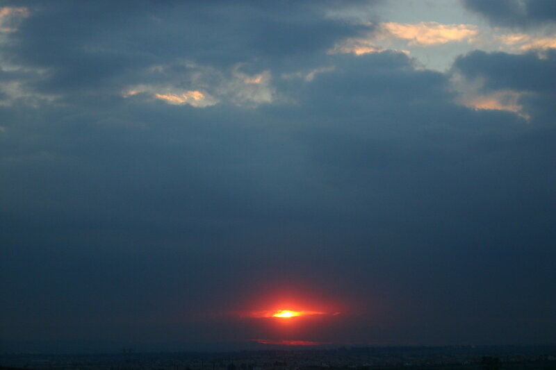 Sun Setting Behind Clouds — Red, Dramatic, Sunset, Photograph, Cityscape