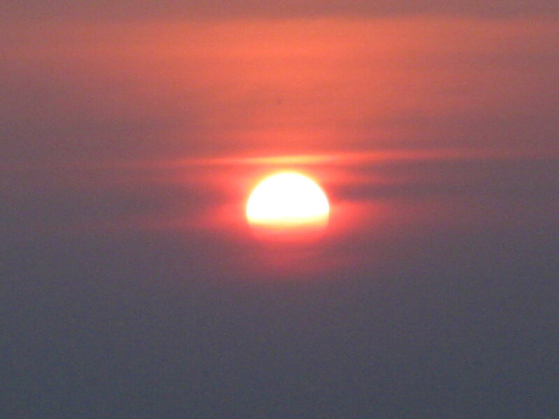 Sun Setting Behind Clouds — Red