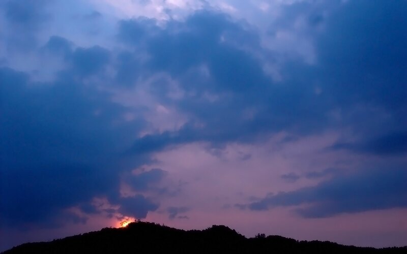 Sun Setting Behind Hill — Blue