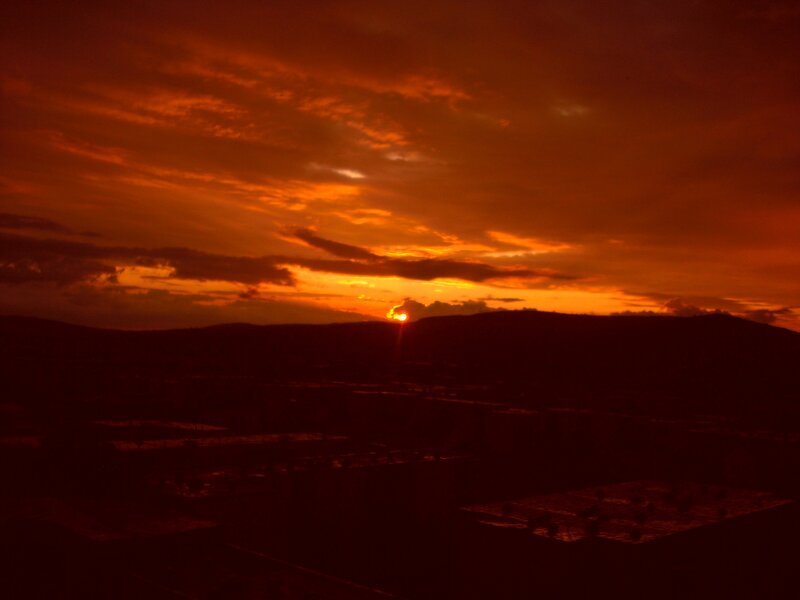 Sun Setting Behind Hills — Orange, Dramatic, Sunset, Photograph, Clouds, Buildings
