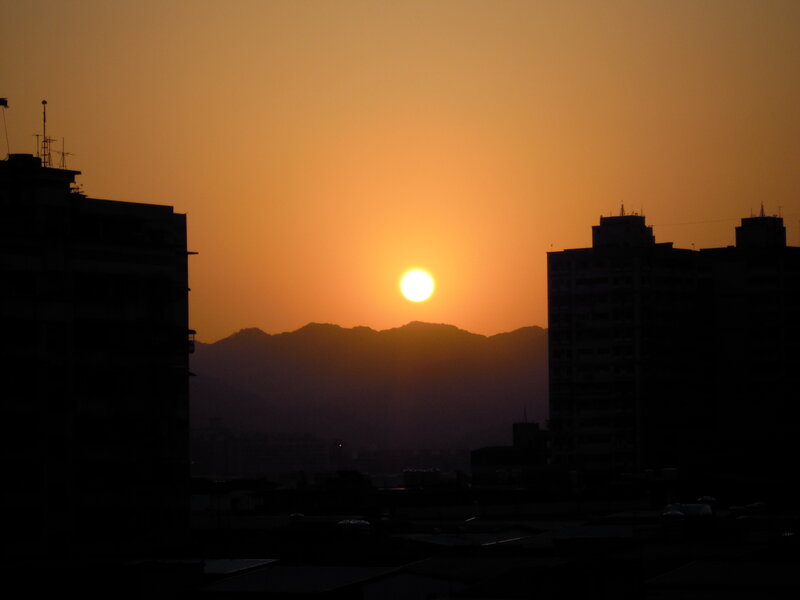 Sun Setting Behind Mountains — Orange, Serene, Sunset, Photograph, Buildings