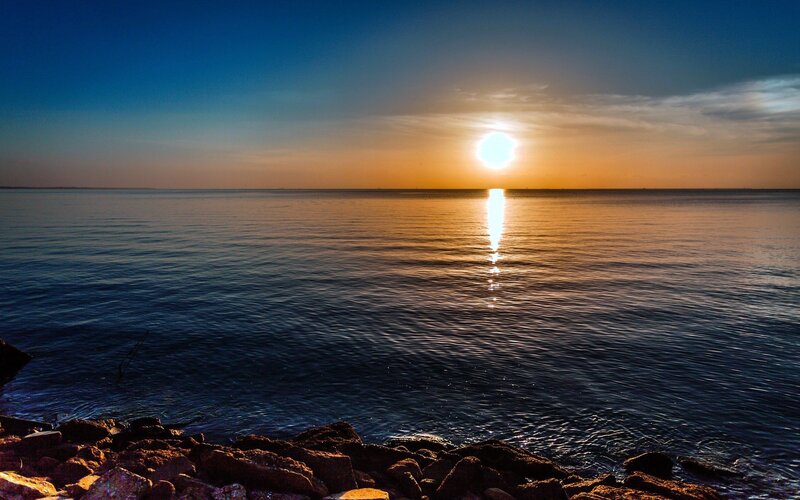 Sun Setting over Ocean — Blue, Serene, Sunset, Photograph, Sky, Rocks