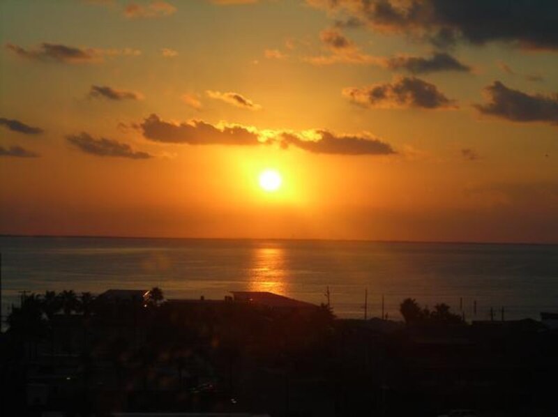 Sun Setting over Ocean — Orange, Serene, Sunset, Photograph, Clouds, Buildings, Palm Trees