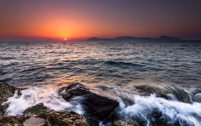 Sun Setting over Ocean — Orange, Serene, Sunset, Photograph, Rocks, Waves, Mountains