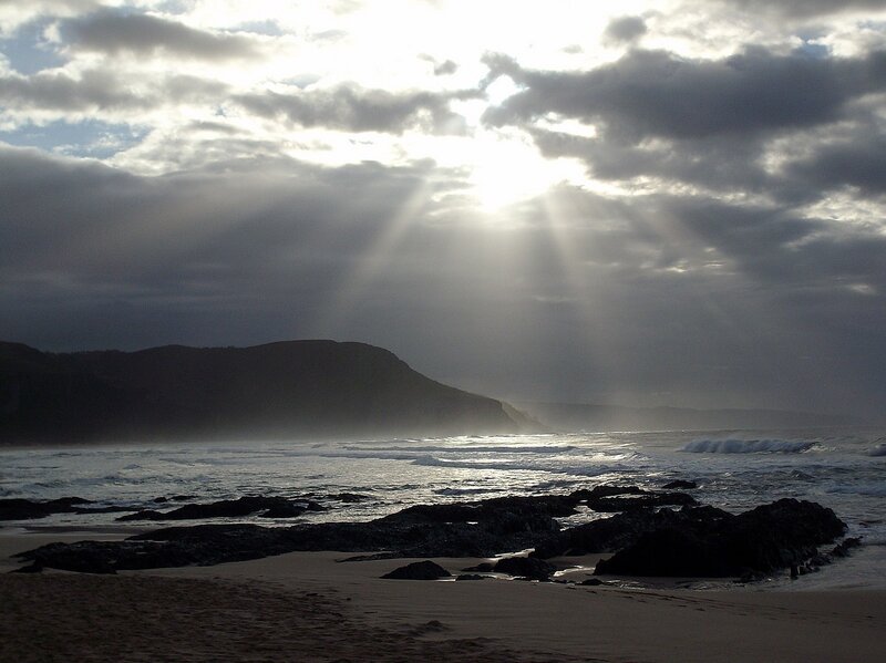 Sunlight beams over a rocky beach