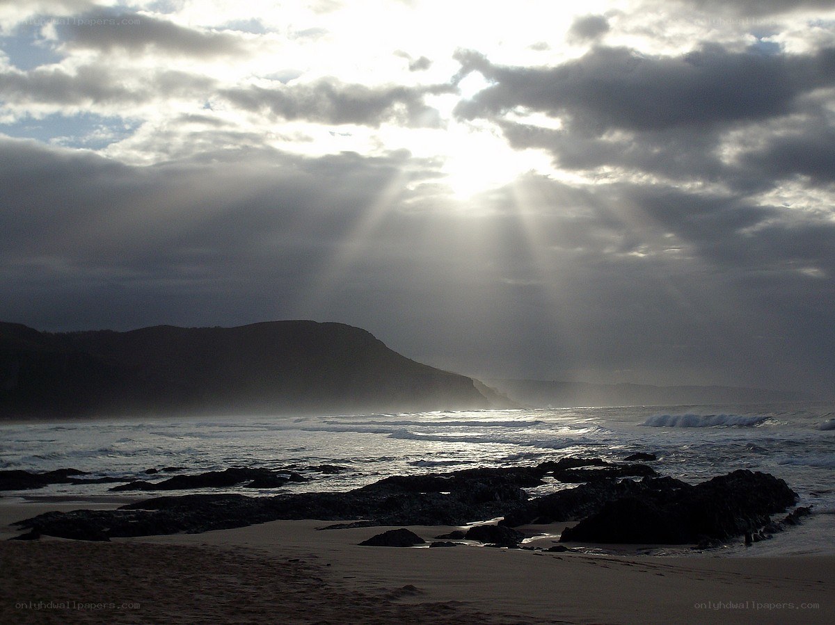 Sunlight beams over a rocky beach
