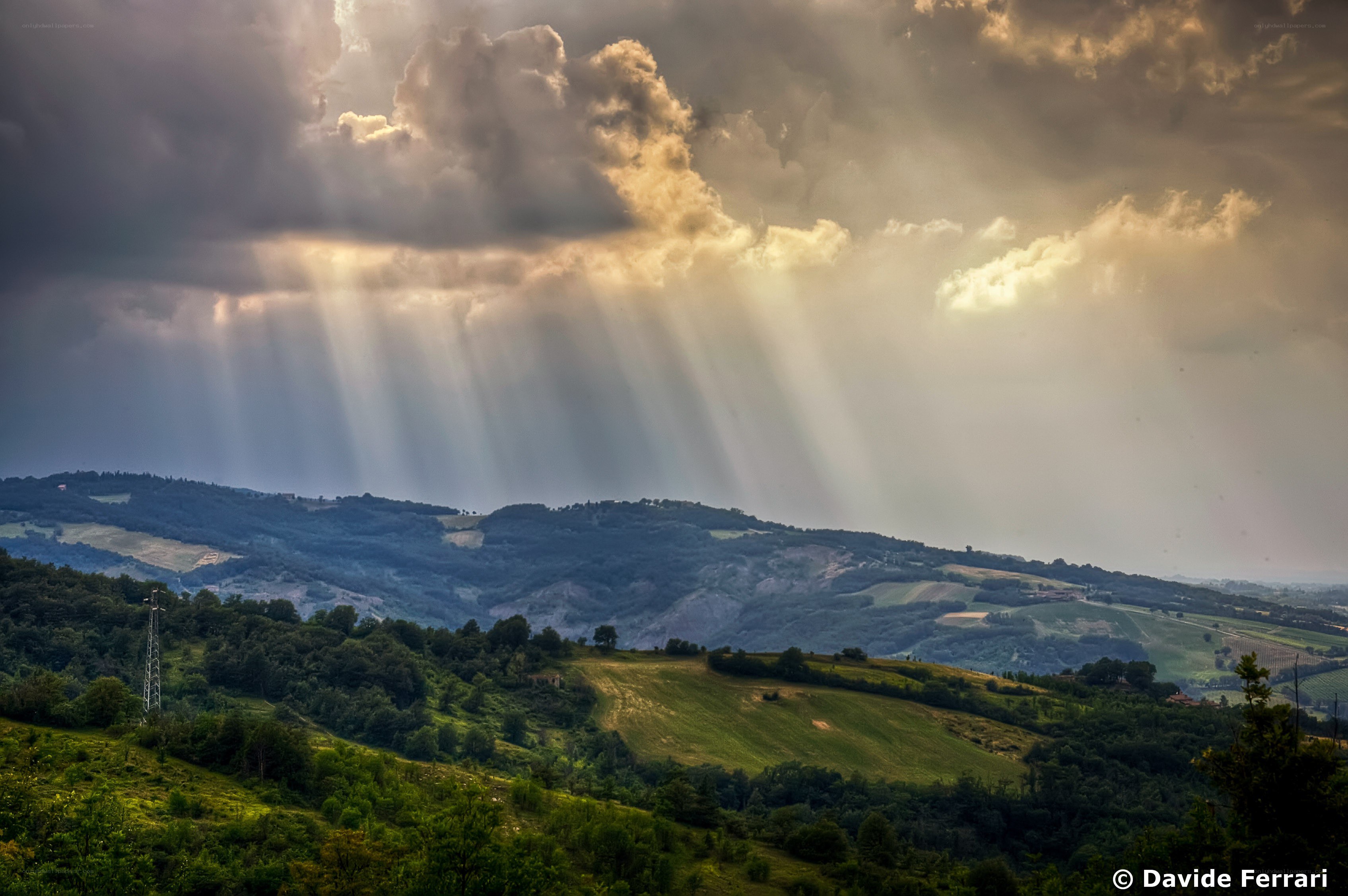 Sunlight beams over rolling hills