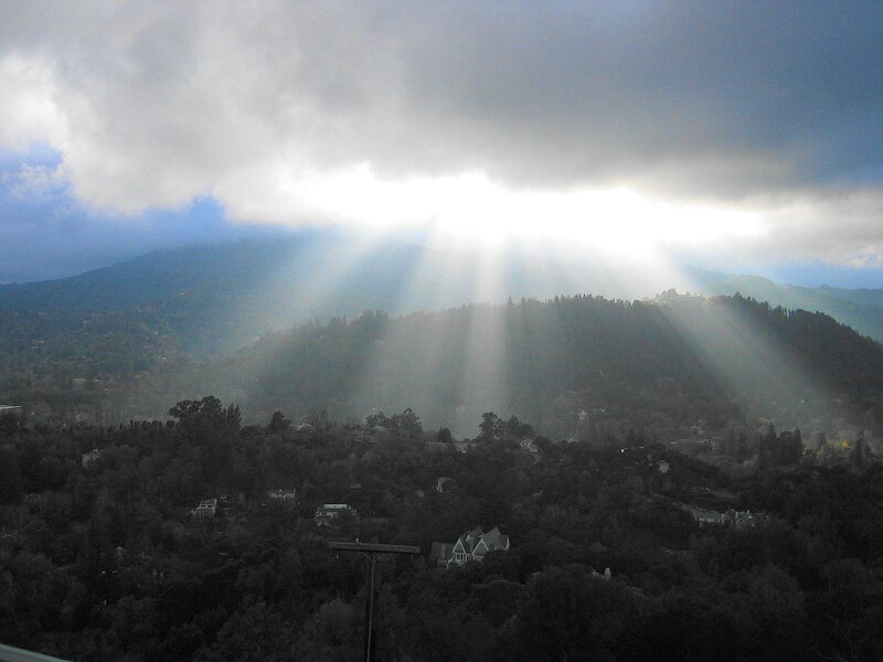 Sunlight beams through clouds over hills