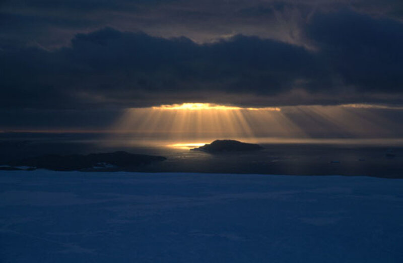 Sunlight breaking through clouds over ice