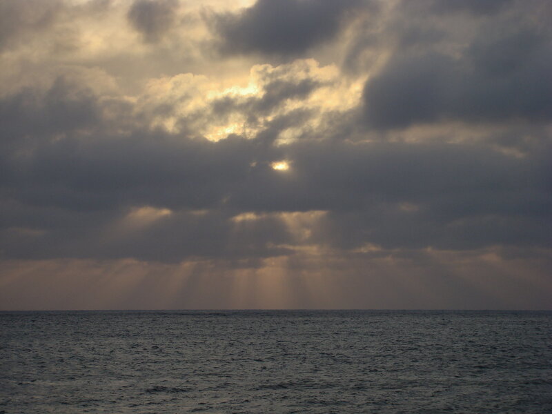 Sunlight breaking through clouds over sea