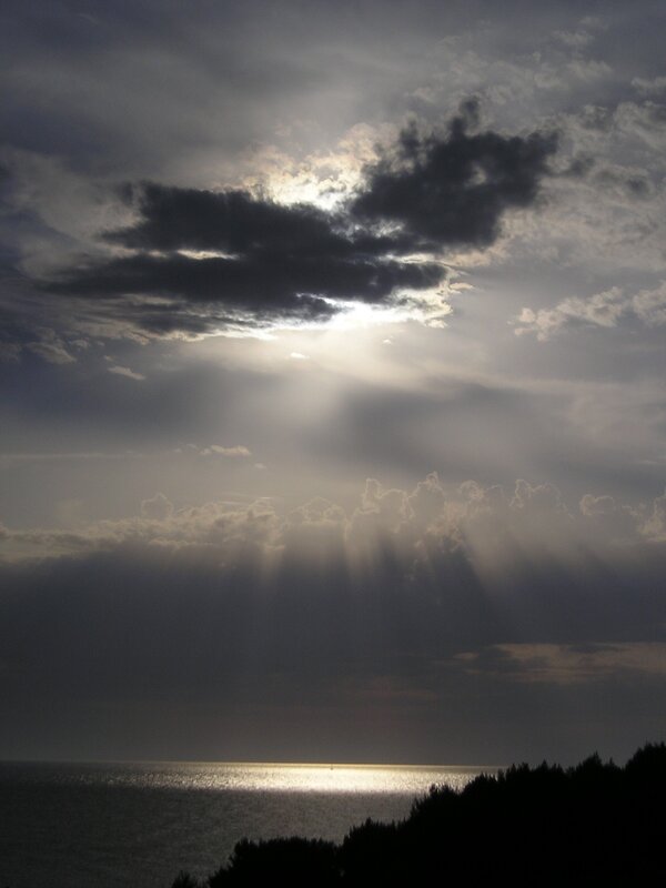 Sunlight breaking through clouds over sea