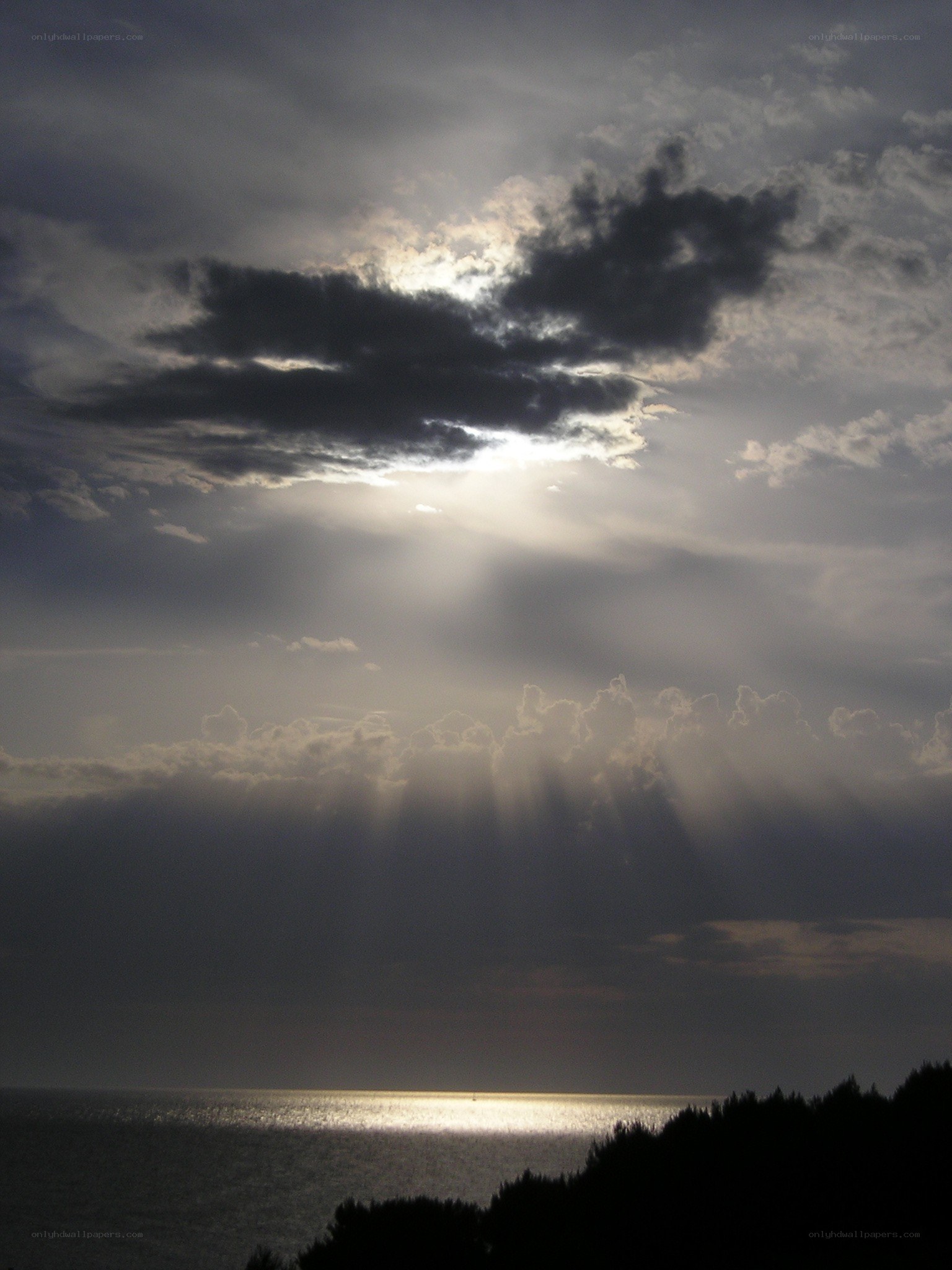 Sunlight breaking through clouds over sea