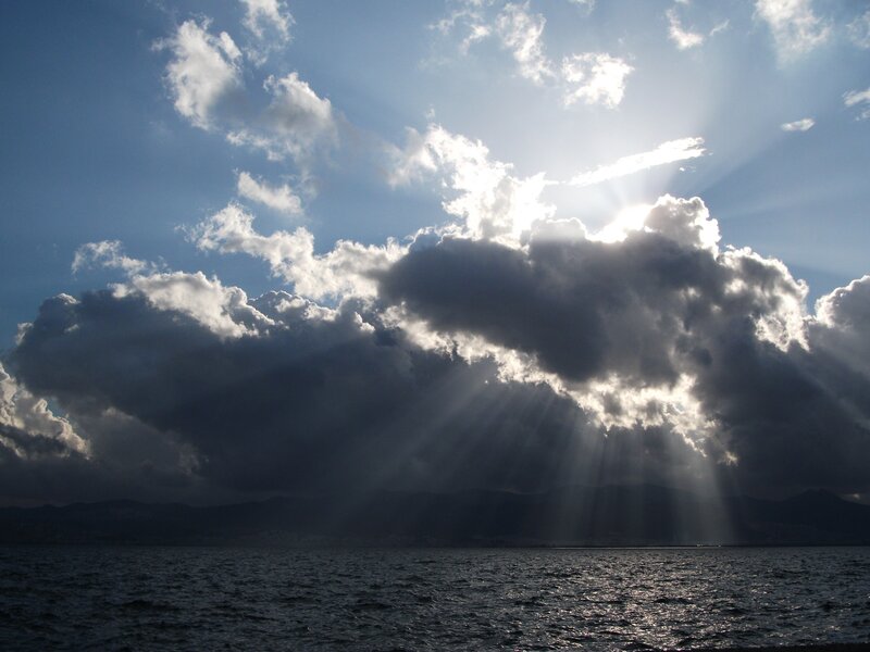 Sunlight breaking through clouds over sea