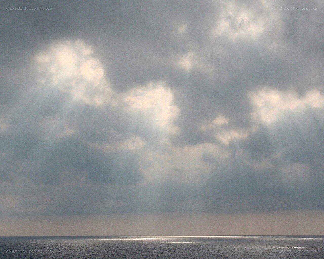Sunlight breaking through clouds over sea