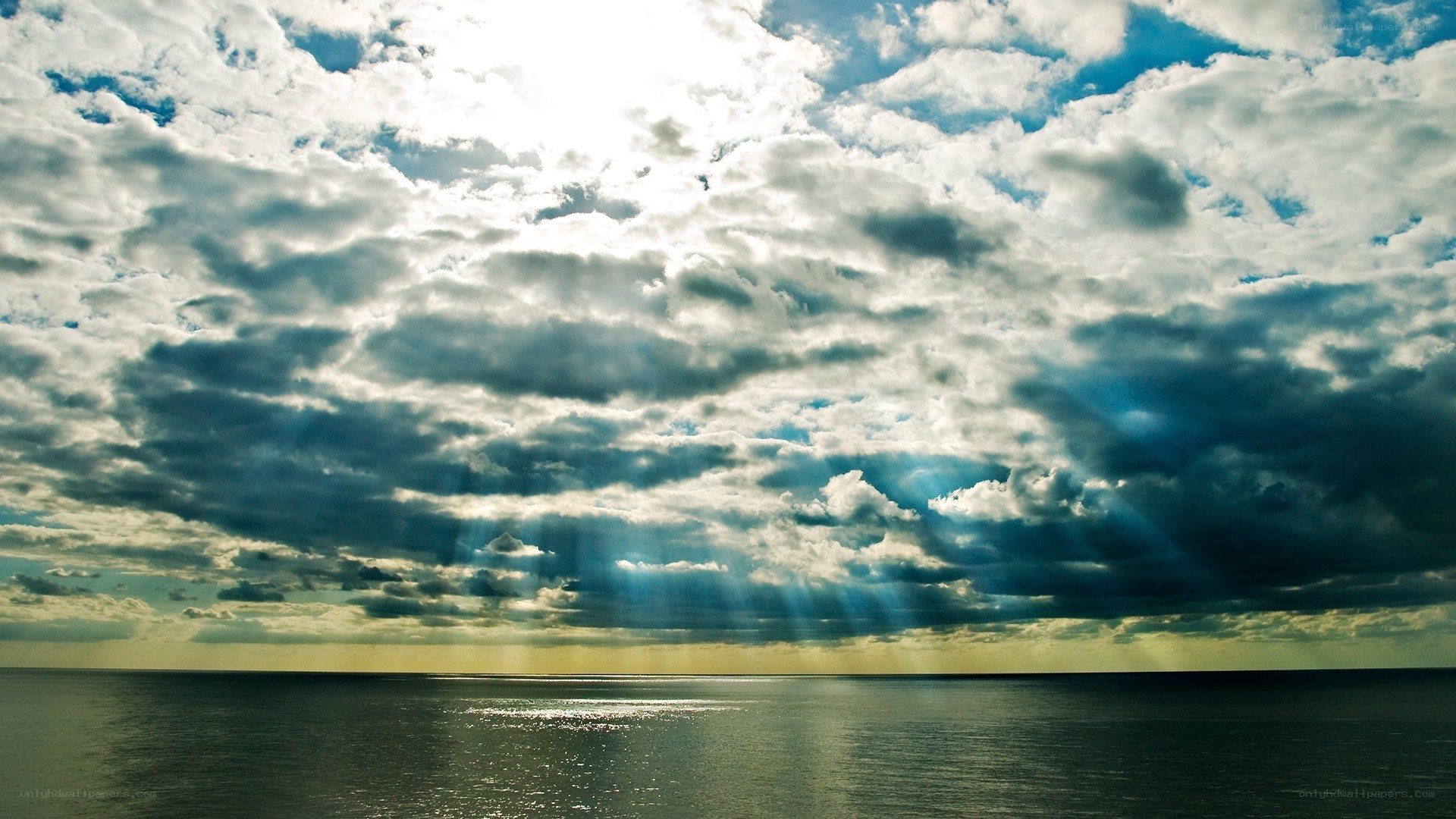 Sunlight breaking through clouds over sea