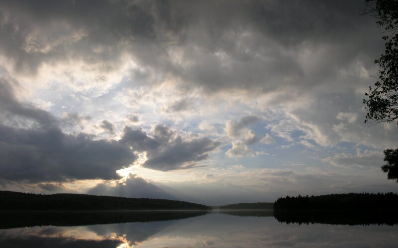Sunlight breaking through storm clouds over a lake