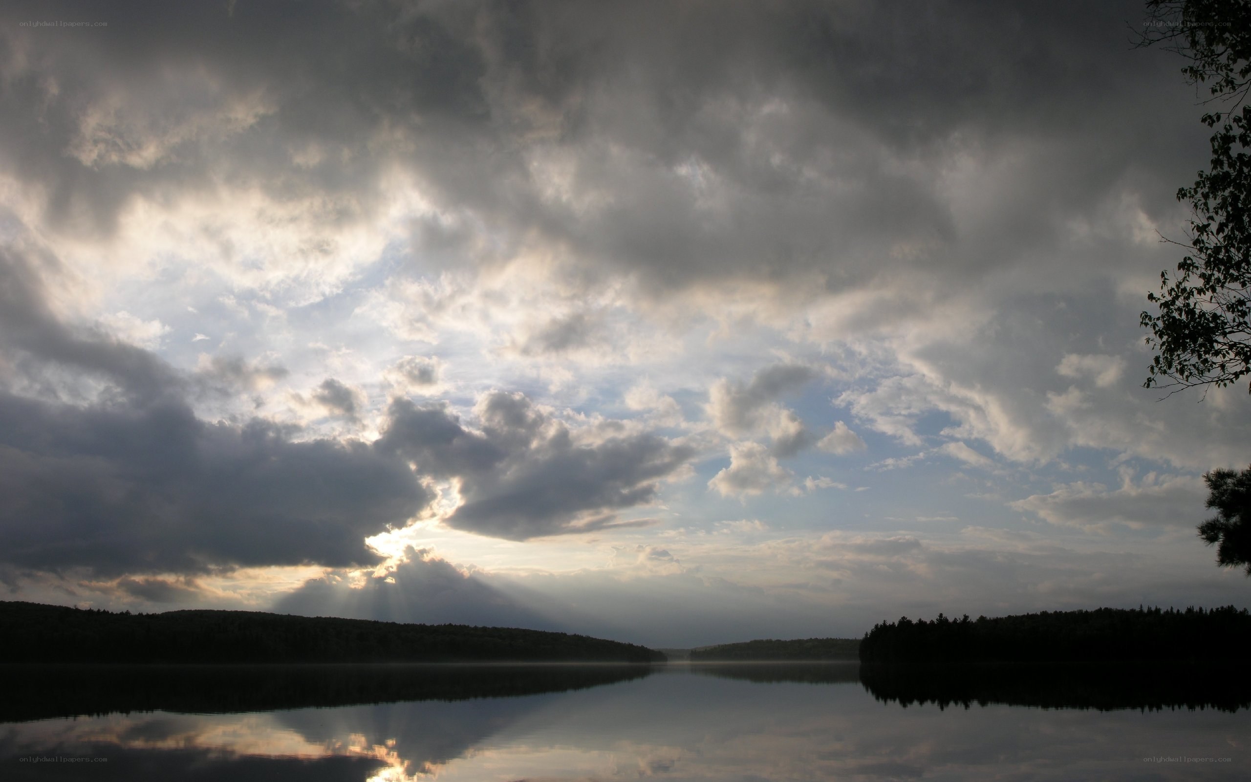 Sunlight breaking through storm clouds over a lake