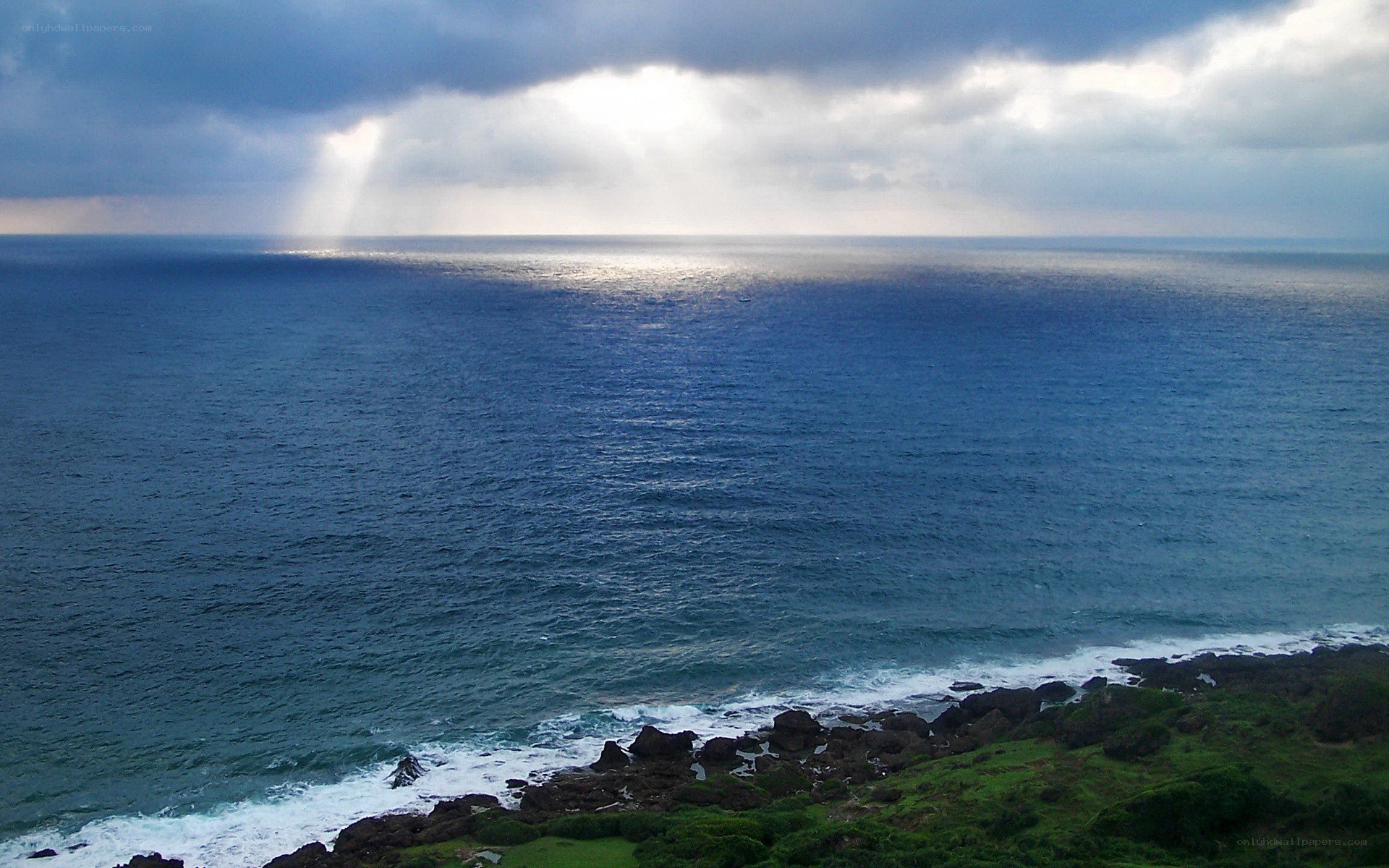 Sunlight breaking through storm clouds over the sea