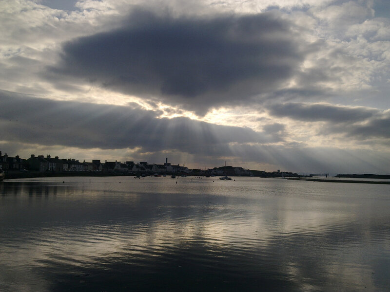 Sunlight breaks through clouds over a coastal town