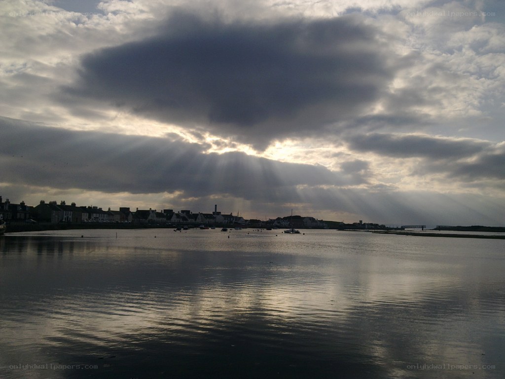 Sunlight breaks through clouds over a coastal town