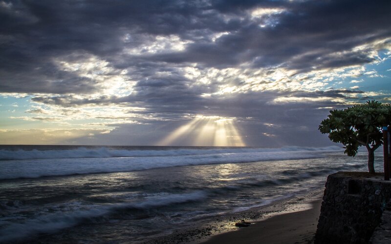 Sunlight breaks through storm clouds at beach