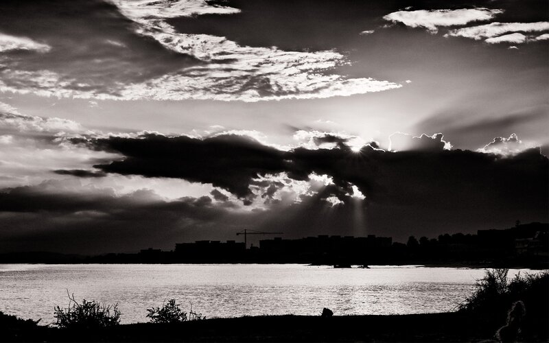 Sunlight Through Clouds — Black, Dramatic, Sunset, Photograph, Water, City Skyline