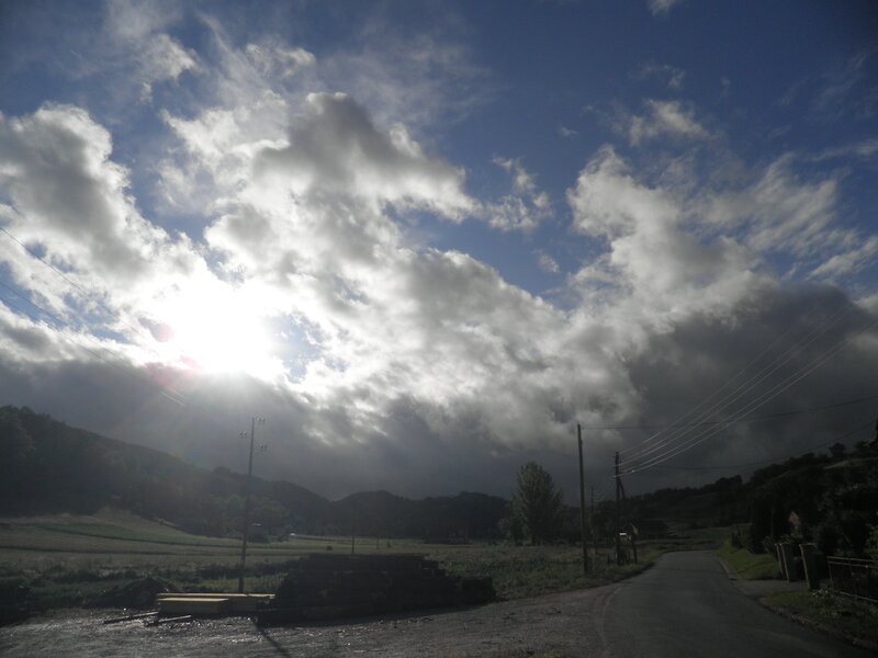 Sunlight through clouds over a rural road