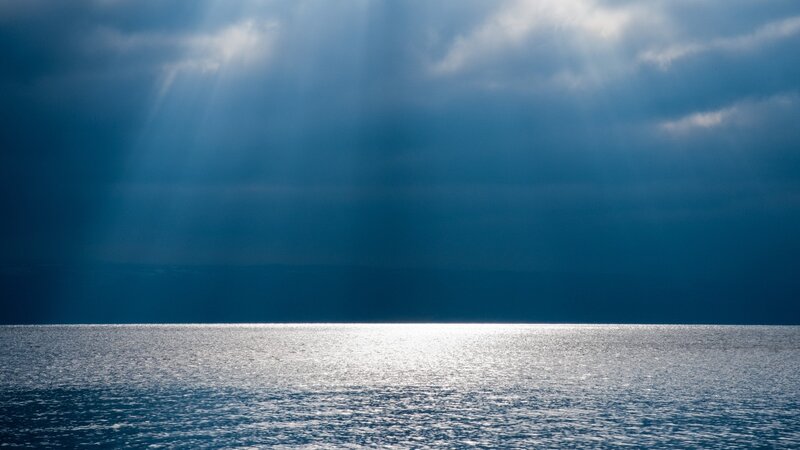 Sunlight Through Clouds over Sea — Blue, Dramatic, Photograph