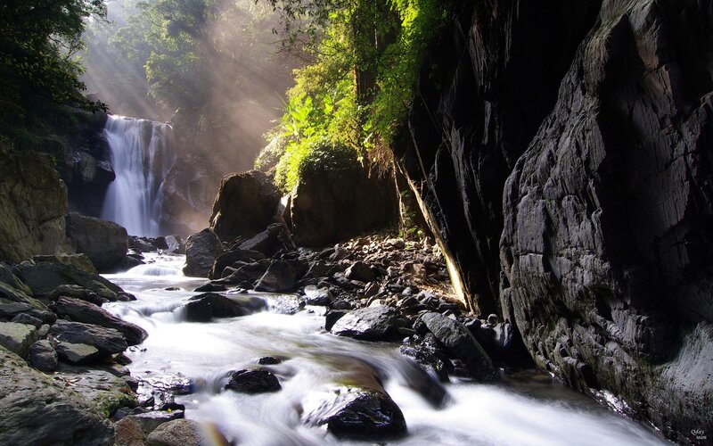 Sunlight through forest waterfall