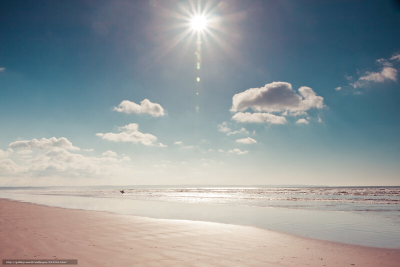 Sunlit beach with surfer