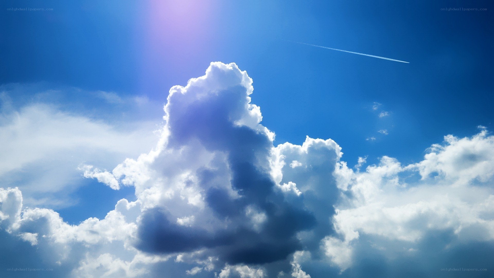 Sunlit clouds with contrail