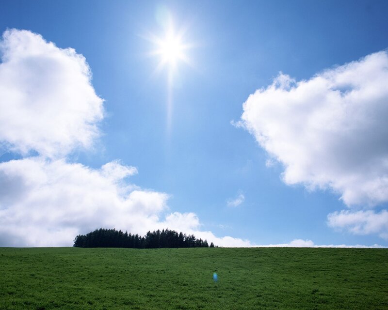 Sunlit green hill with clouds