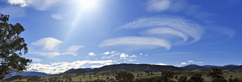Sunlit hills with spiral clouds