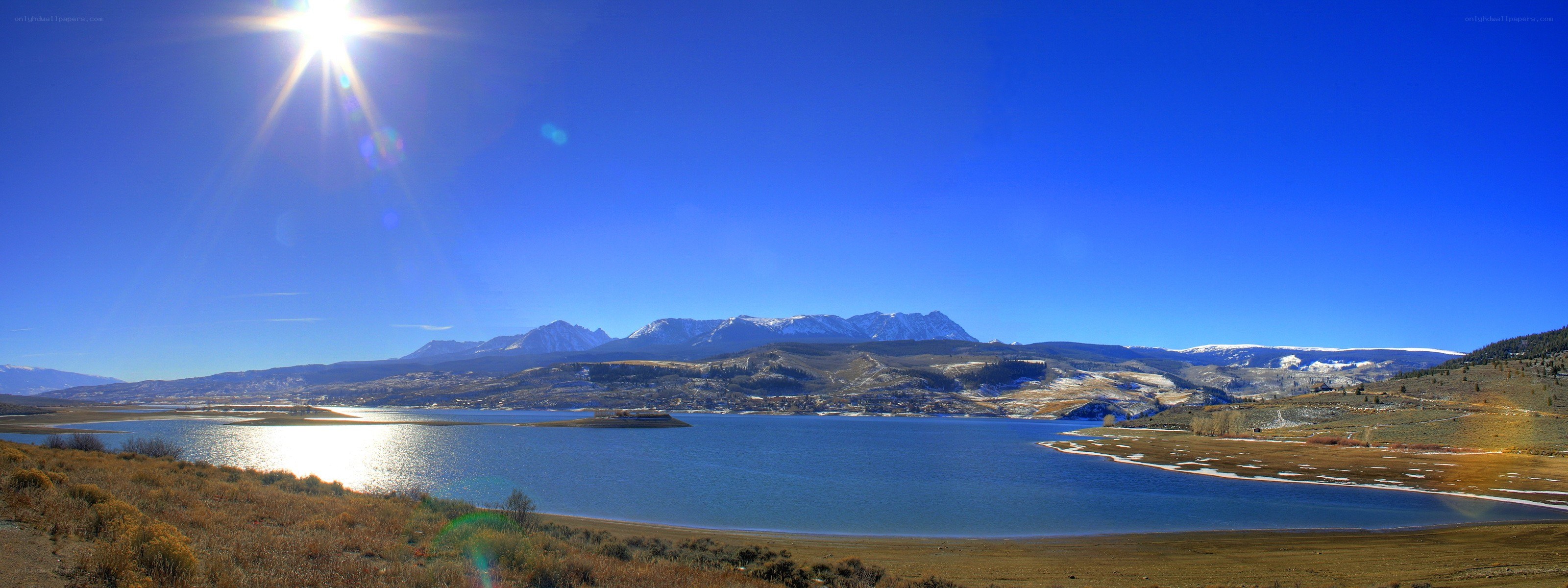 Sunlit lake with snow-capped mountains