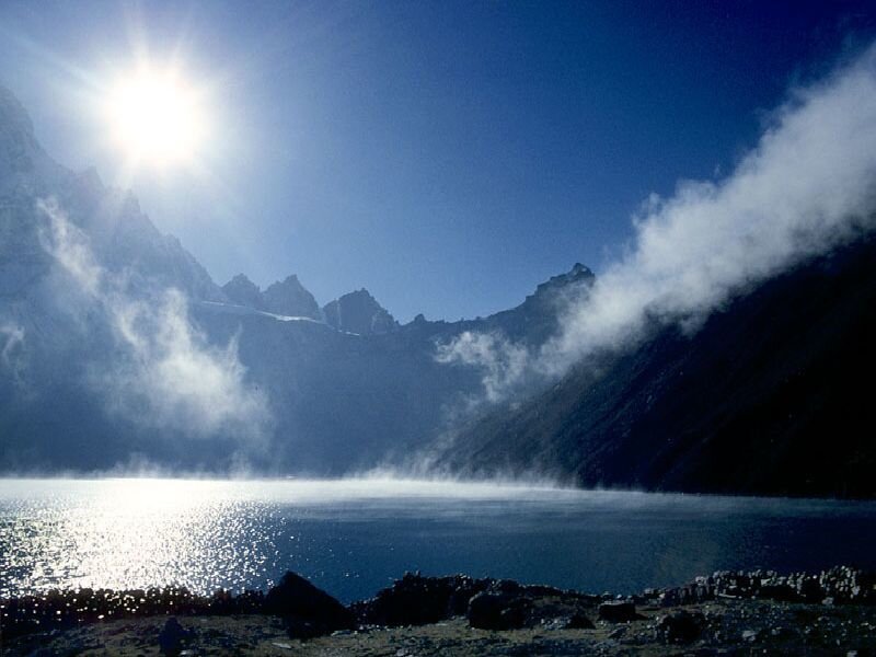 Sunlit mountain lake with mist
