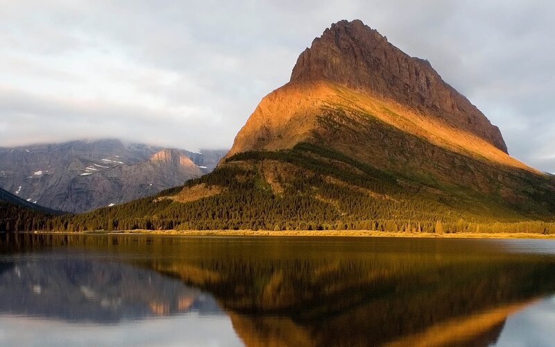 Sunlit mountain reflected in lake