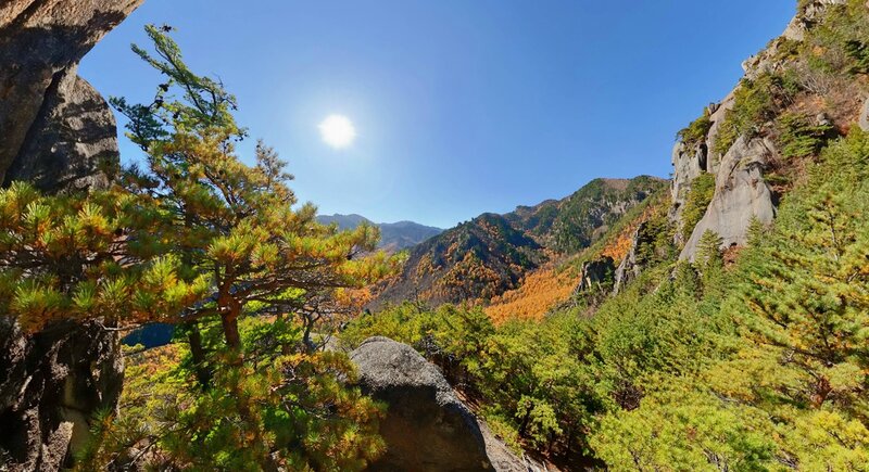 Sunlit mountain valley with autumn trees