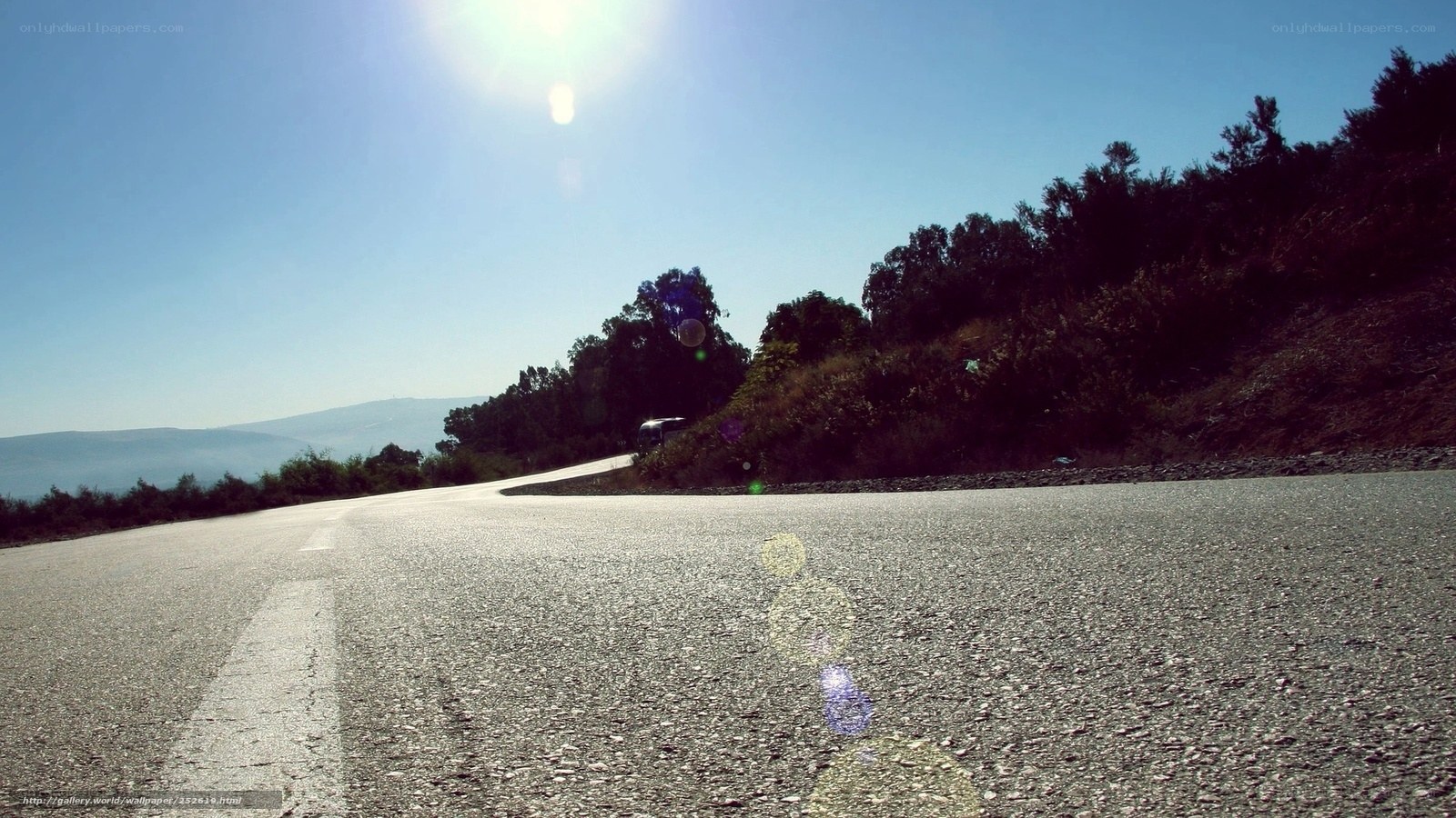 Sunlit road winding through hills