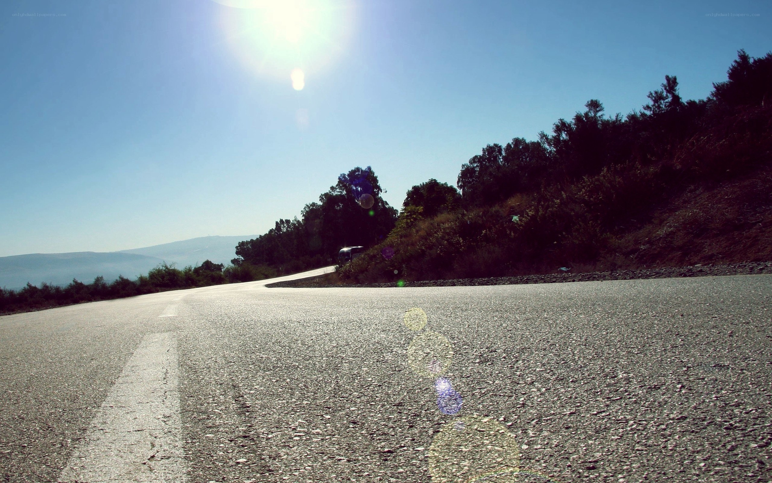 Sunlit road winding through hills