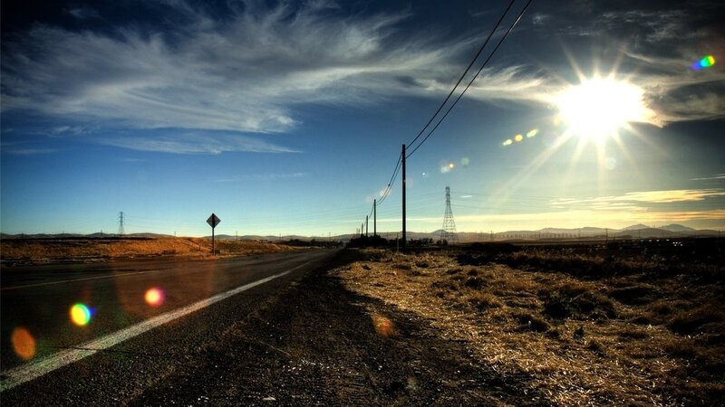 Sunlit road with power lines