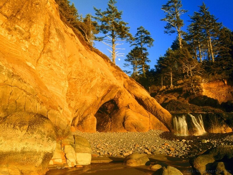 Sunlit rock arch and waterfall