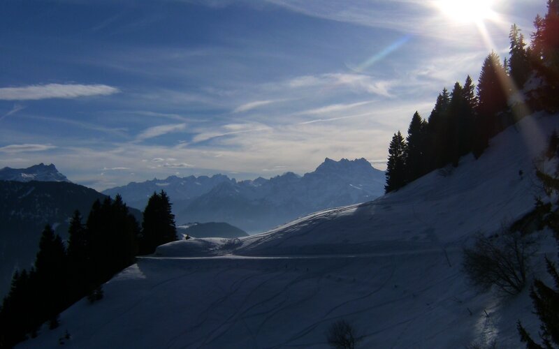 Sunlit ski slope with mountains