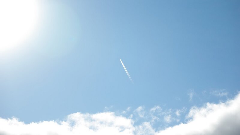 Sunlit sky with airplane trail