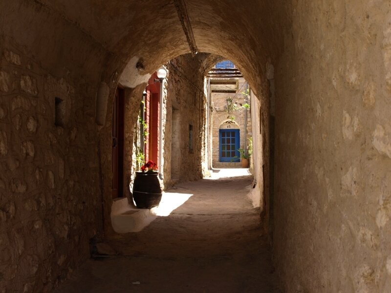 Sunlit stone alley with blue door
