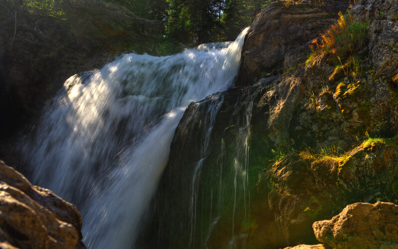 Sunlit waterfall in forest