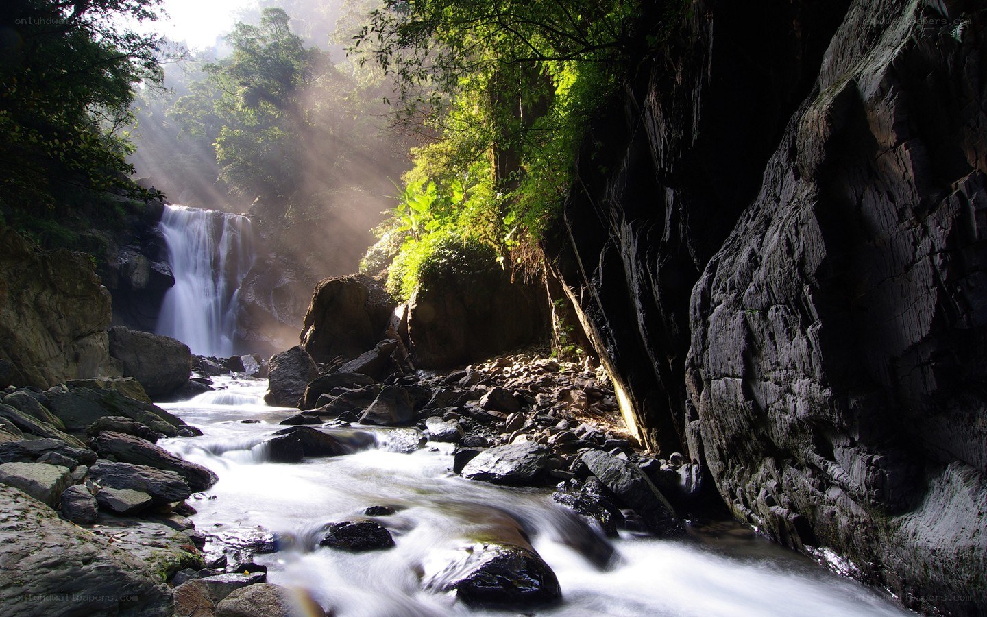 Sunlit waterfall in forest canyon