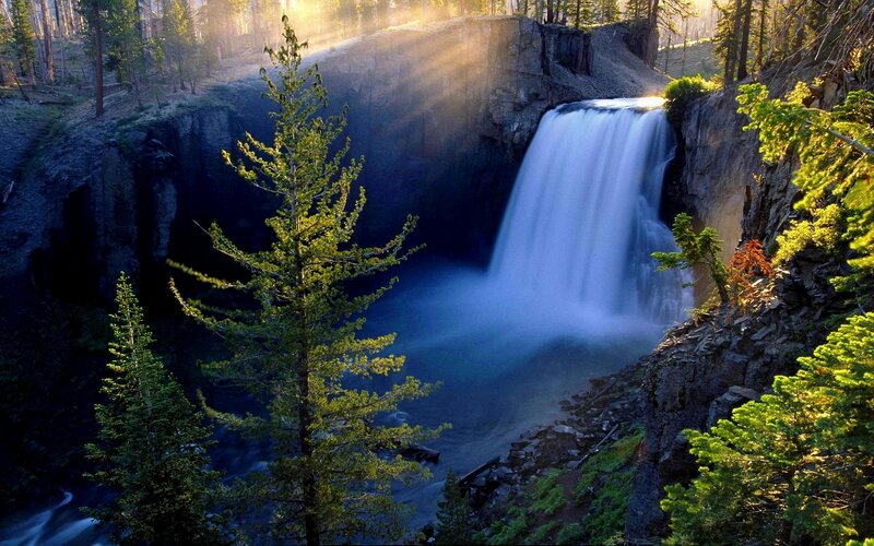 Sunlit waterfall in forest canyon