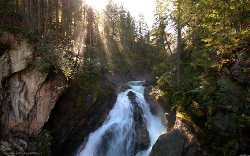 Sunlit waterfall in forest canyon