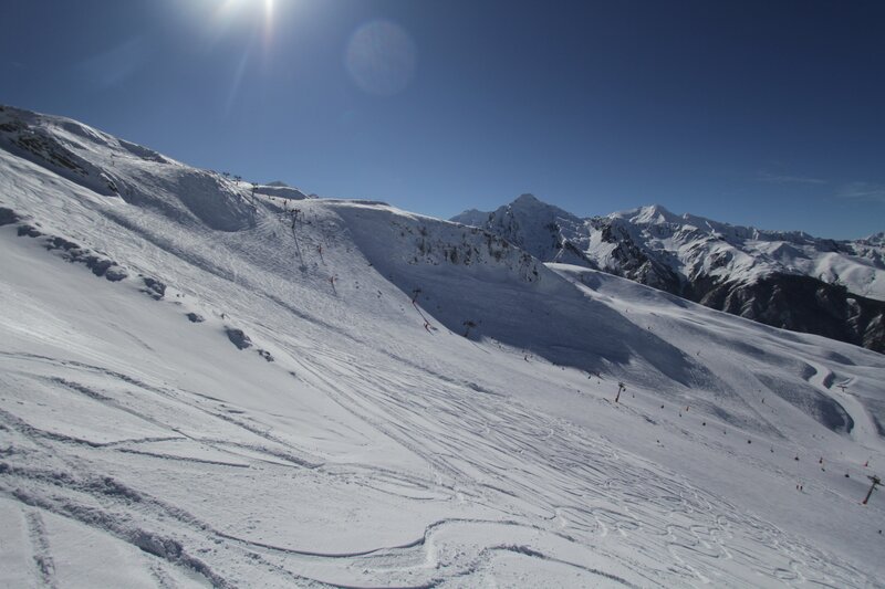 Sunny ski slope with mountains